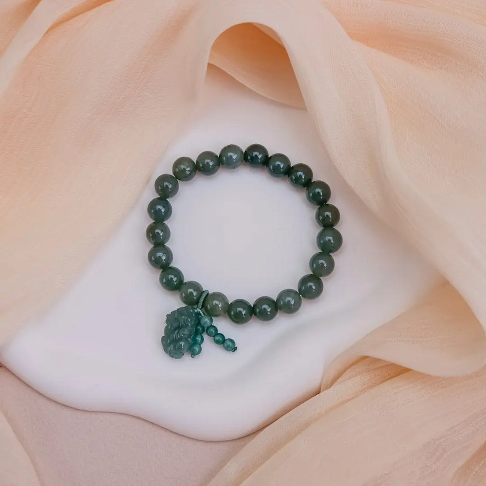 A green beaded bracelet rests on draped fabric. - Photo by Keekon on Unsplash
