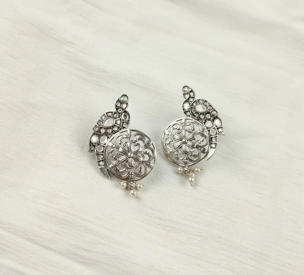 a pair of silver colored earrings on a white background - Photo by Johny Silver on Unsplash