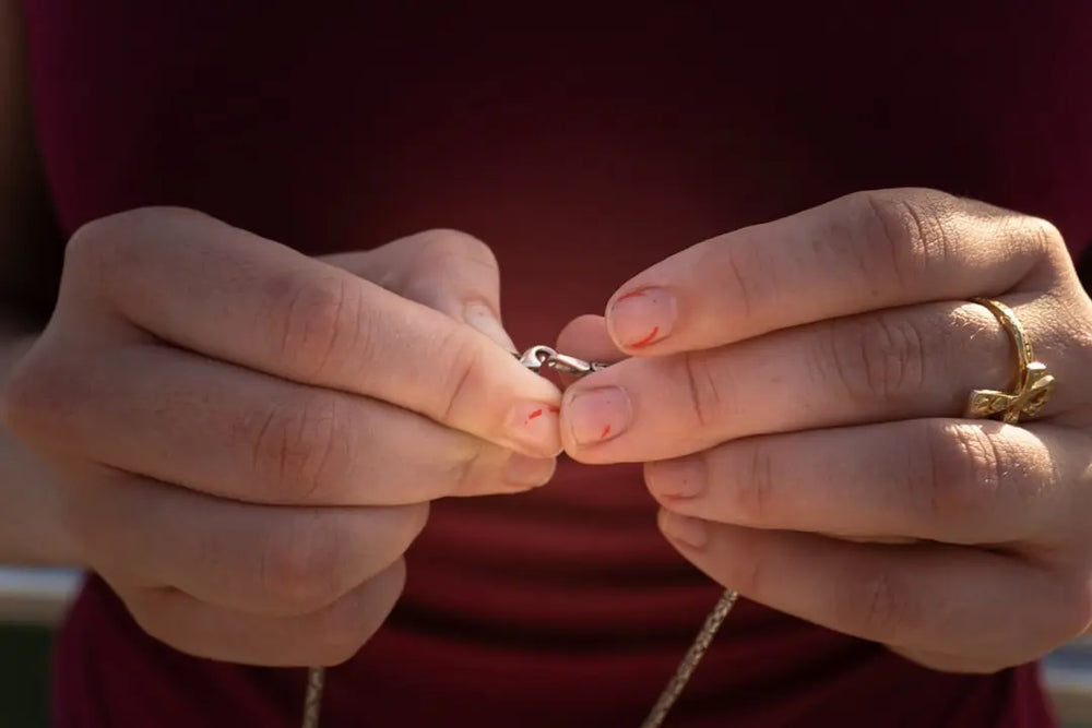 Woman fastens a necklace clasp with her hands - Photo by Zulfugar Karimov on Unsplash