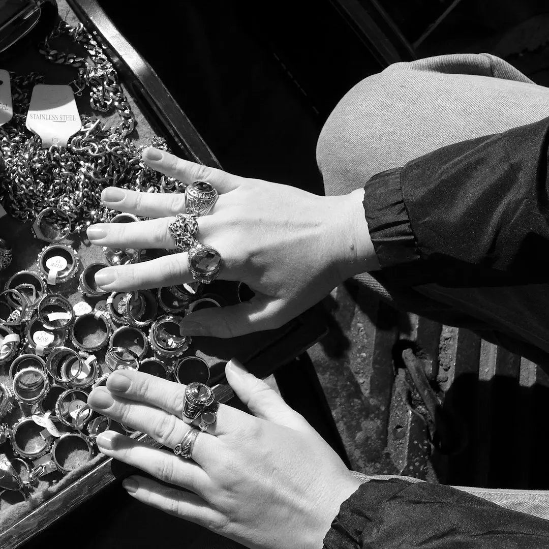 Hands adorned with ornate rings examining jewelry display - Photo by Aleksandr Dalakian on Unsplash
