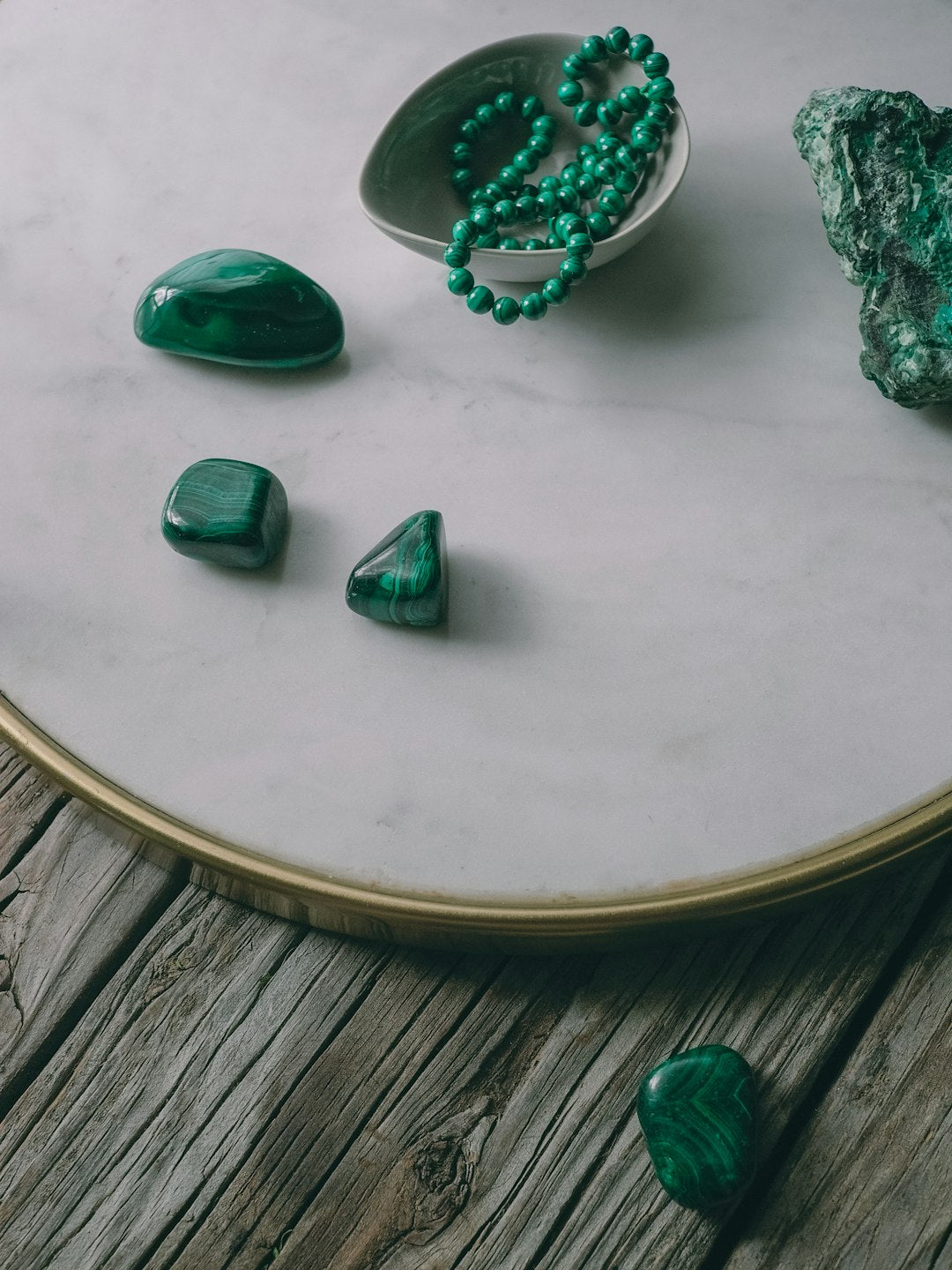 a table topped with green stones and a bowl of green beads - Photo by Laura Olsen on Unsplash