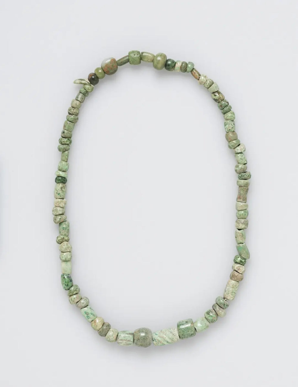 A necklace made of various green and beige beads. - Photo by The Cleveland Museum of Art on Unsplash