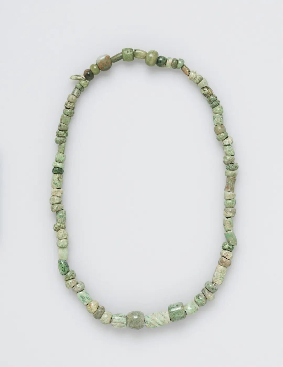 A necklace made of various green and beige beads. - Photo by The Cleveland Museum of Art on Unsplash
