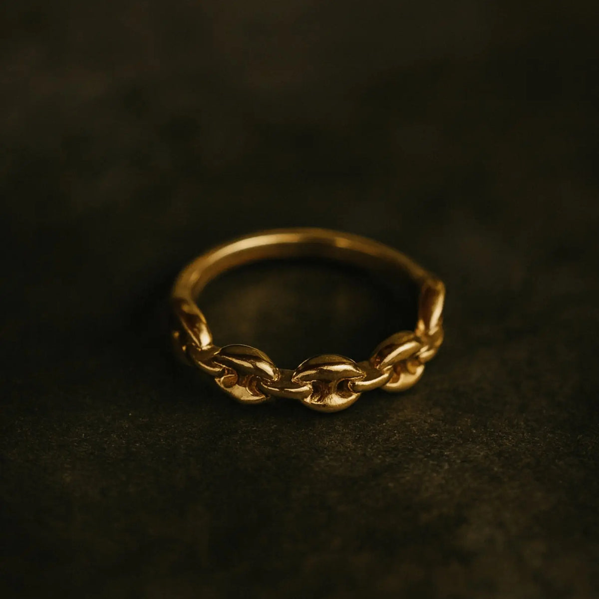 Gold chain ring on a dark textured background
