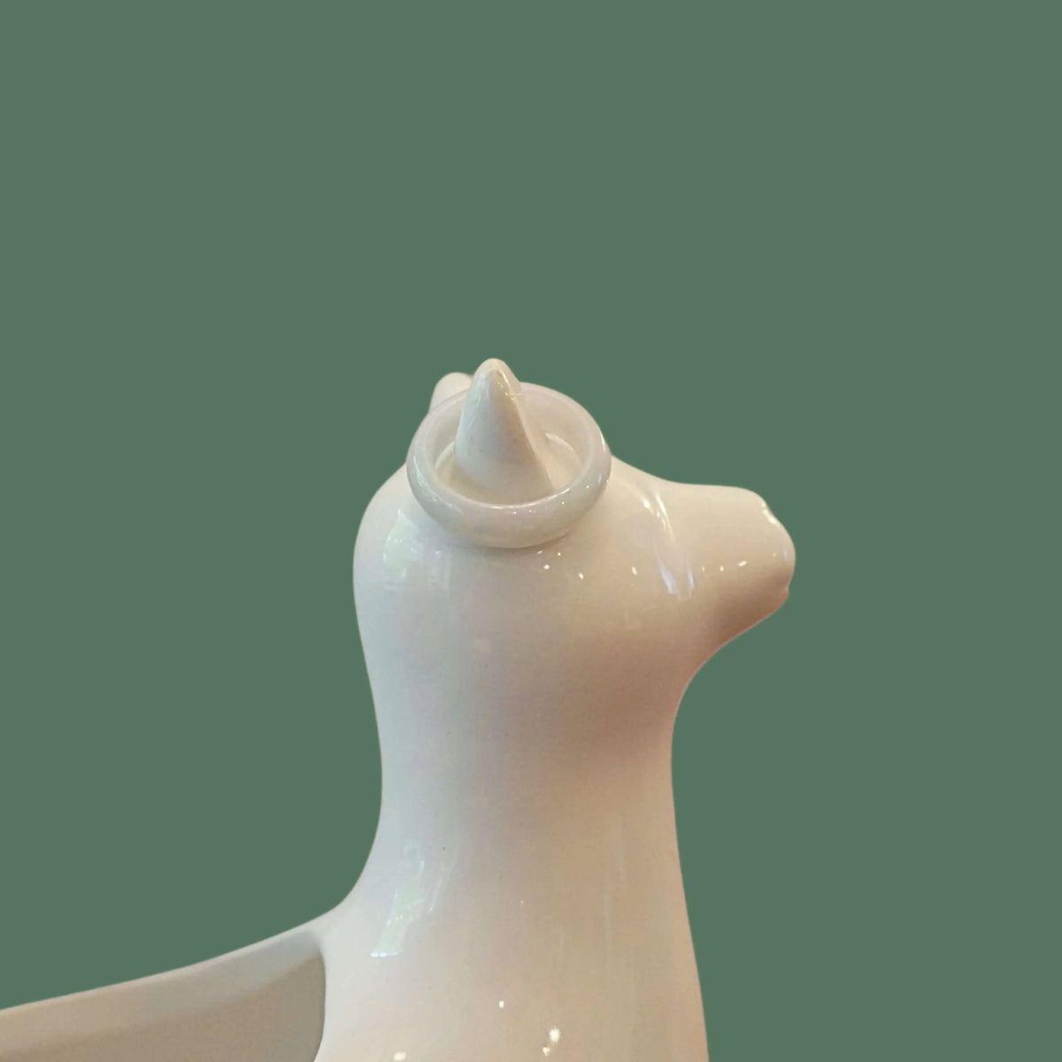 White ceramic seal figurine on a green background