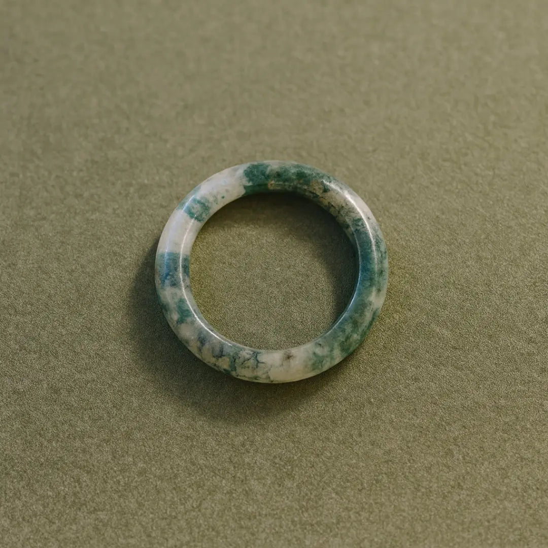 Top view of Hand-carved Somae Moss Agate Ring with natural green inclusions, minimalist round band displayed on neutral background