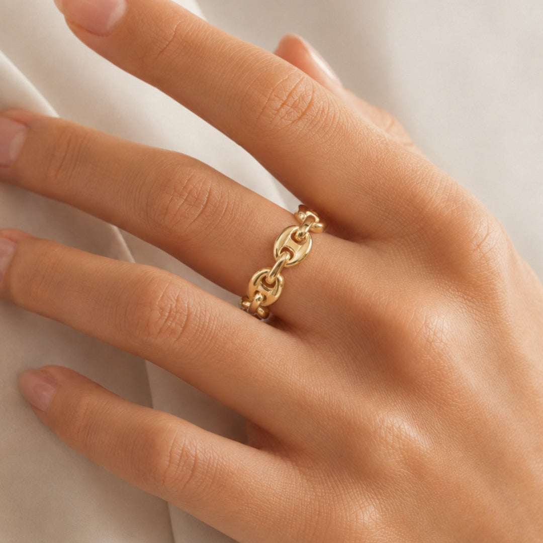 Gold ring on a person's finger against a neutral background