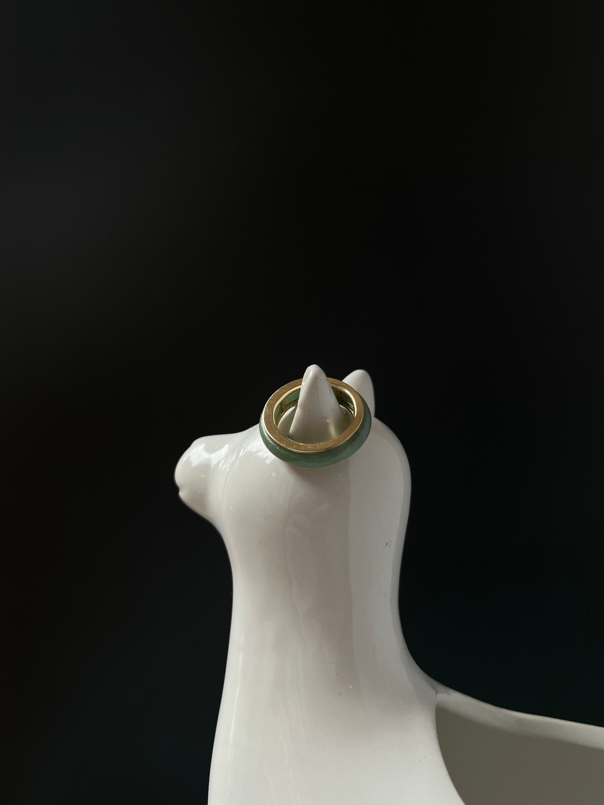 Close-up of jadeite stone on Jaura Ring, capturing natural texture and color variations on a Lama statue.