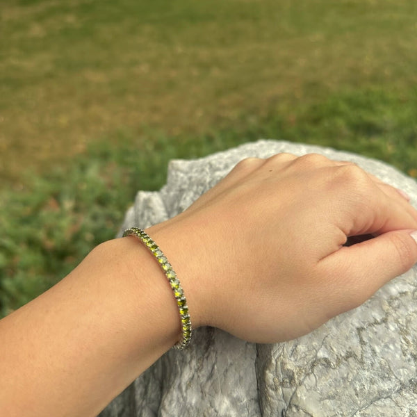 Hand wearing a bracelet with grass in the background