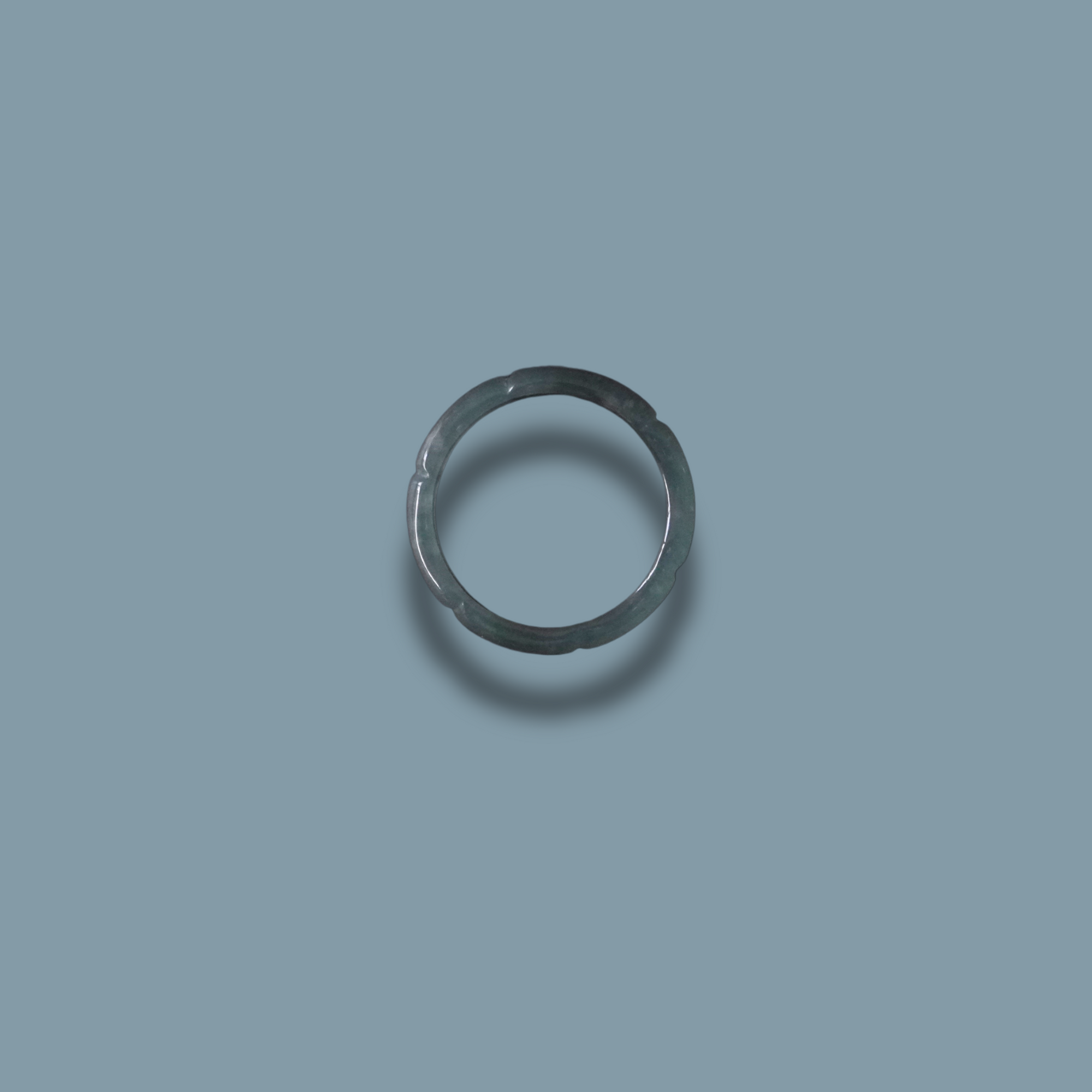 Elegant green Jadeite ring with detailed carvings, displayed on a dark green background.