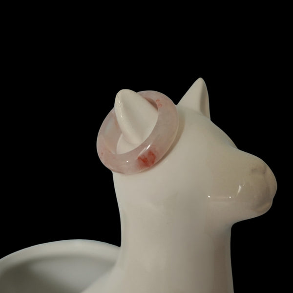 Light Ping Meihua ring on white ceramic cat jewelry holder, minimalist product display on black background.