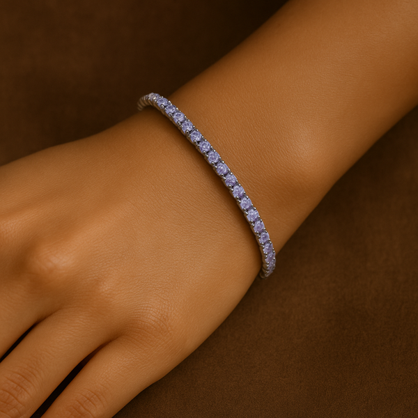 Silver bracelet with small stones on a wrist against a brown background