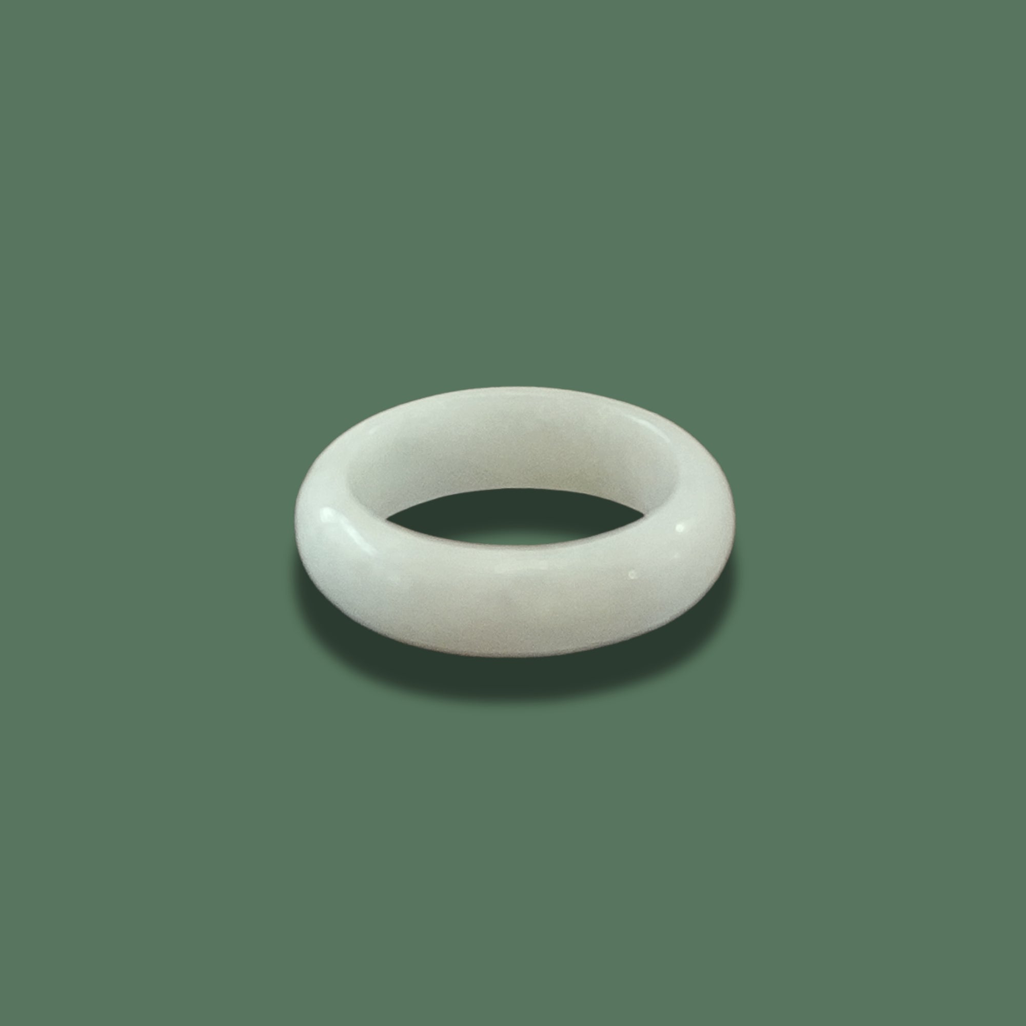 White jadeite ring (Nivelle Ring) displayed on a soft green background, highlighting its smooth, polished surface and minimalist design.