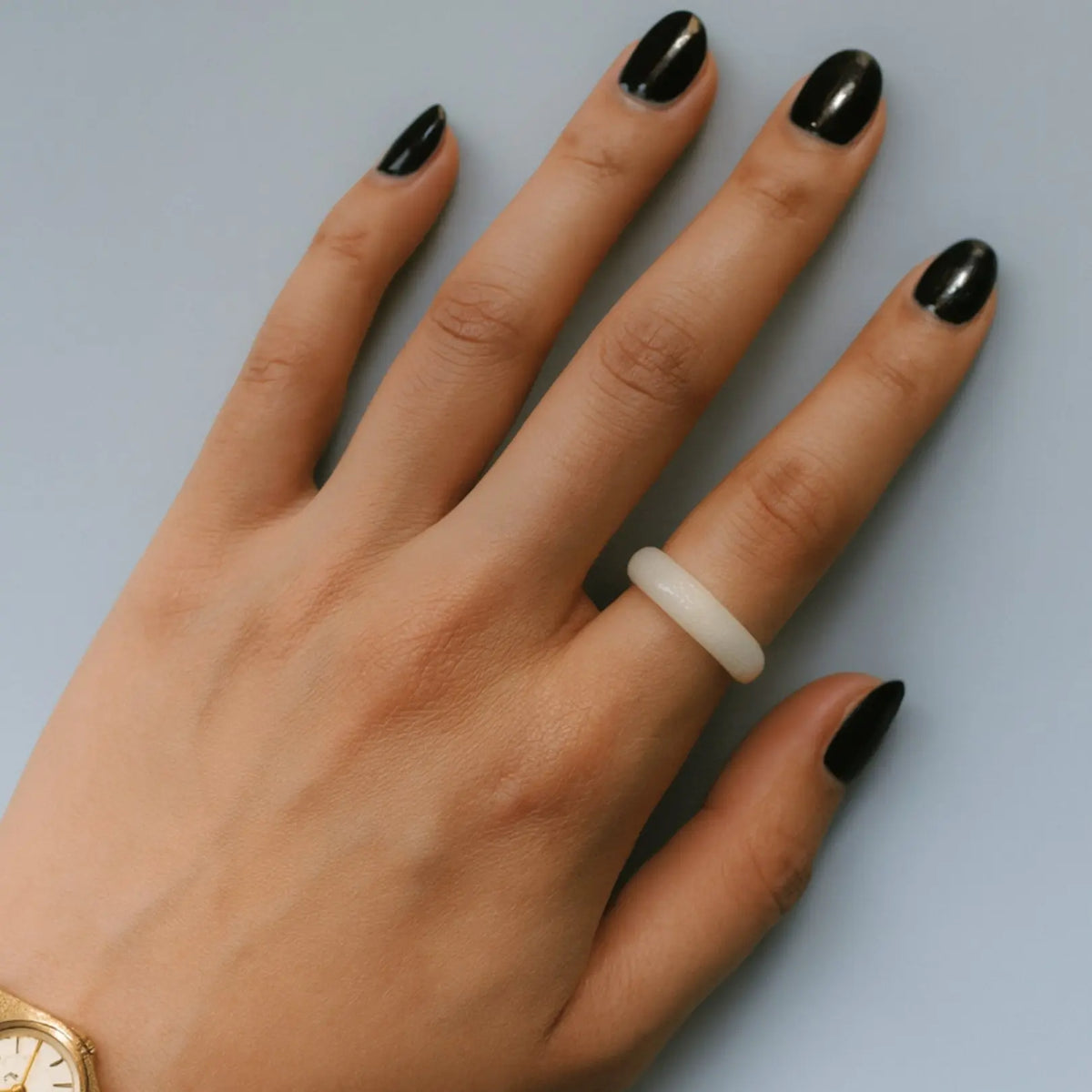 Top angle of White jadeite ring (Nivelle Ring) displayed on a soft green background, highlighting its smooth, polished surface and minimalist design.