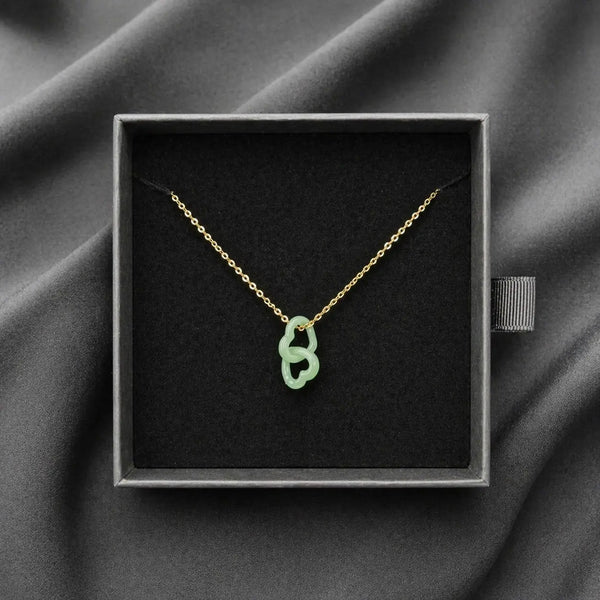 Necklace with a green pendant in a black box on a gray fabric background