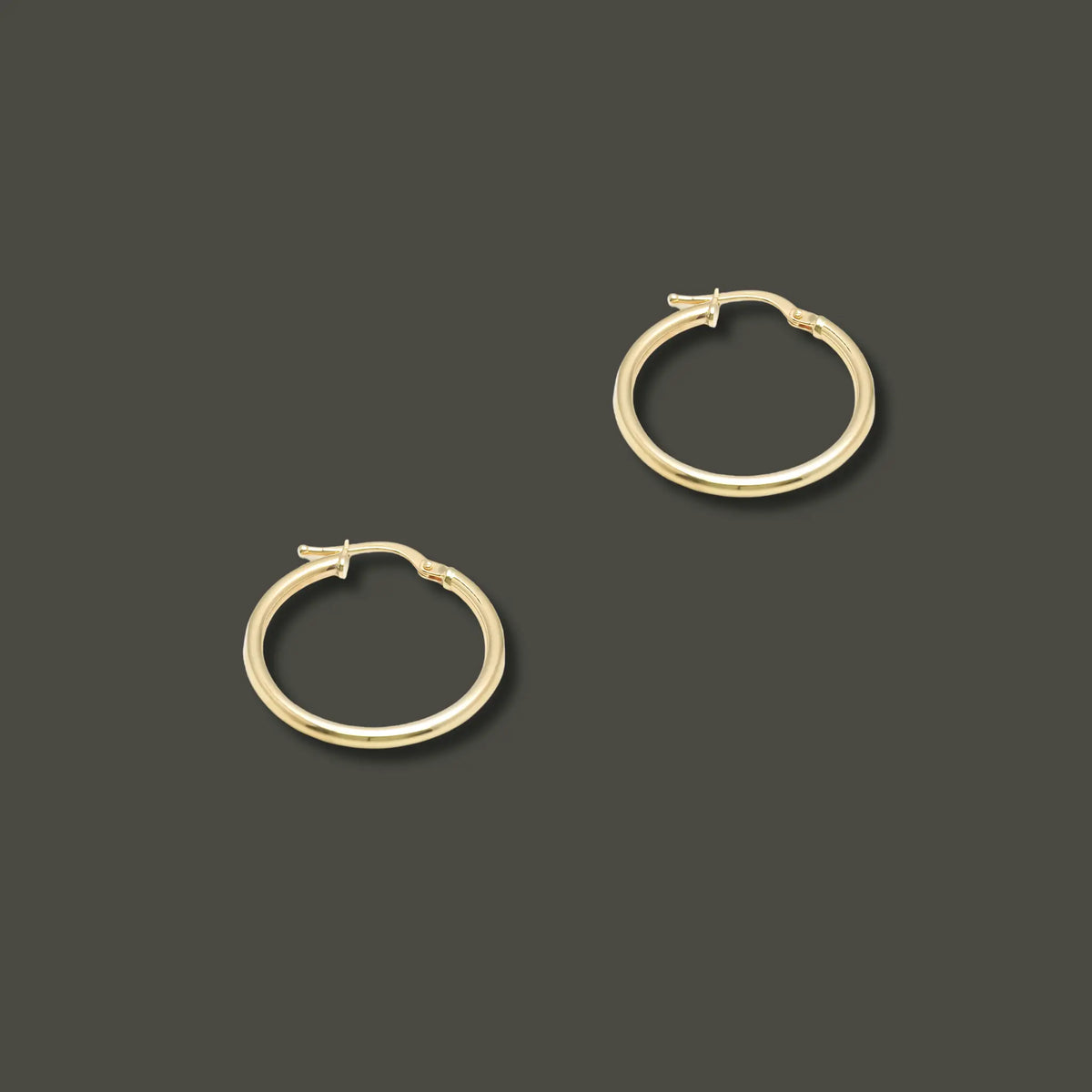 Close-up of polished 10K yellow gold hoop earrings, 20mm in diameter, lightweight and minimal, designed for everyday elegance.