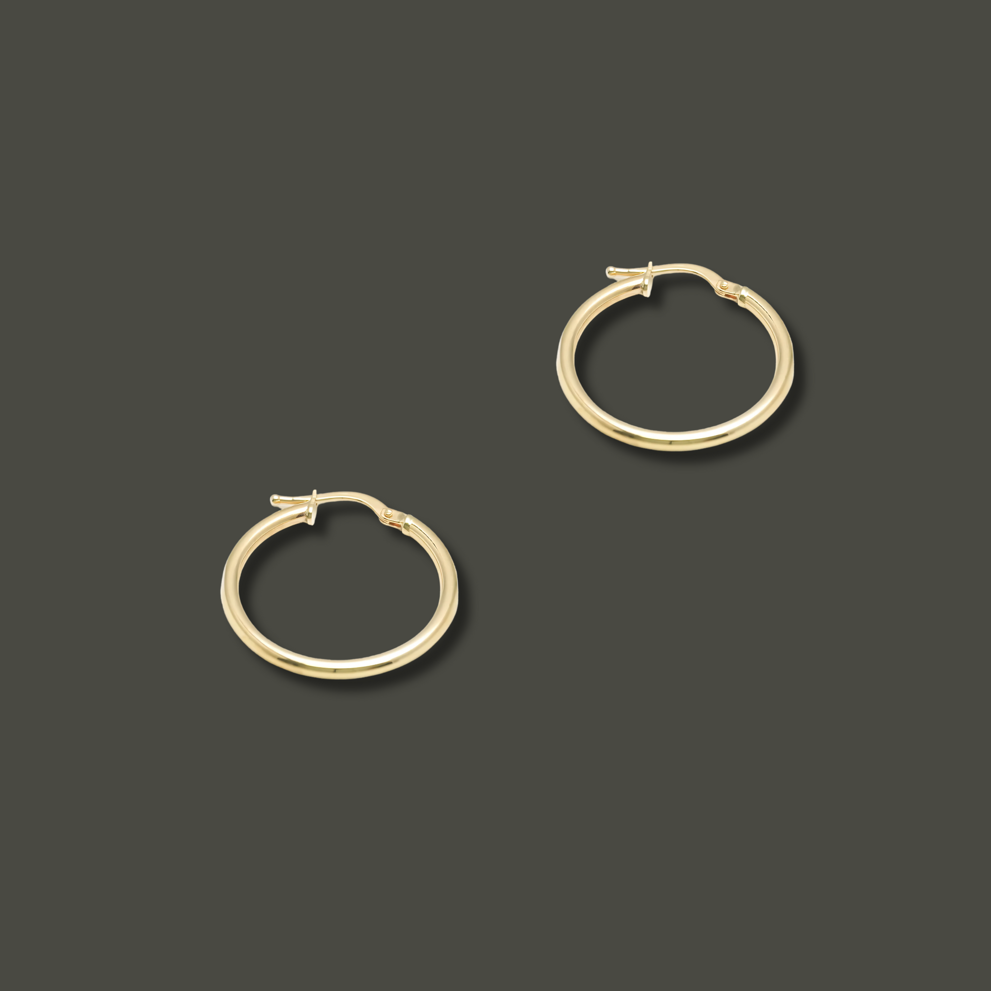 Close-up of polished 10K yellow gold hoop earrings, 20mm in diameter, lightweight and minimal, designed for everyday elegance.