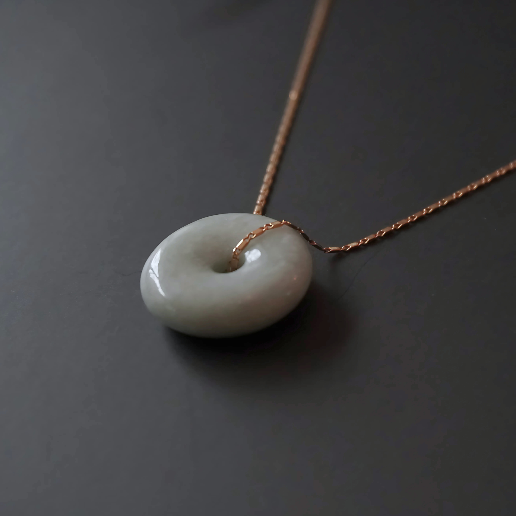 Close-up of the Yuán Jade Necklace featuring a circular jade pendant on a 10K gold chain.