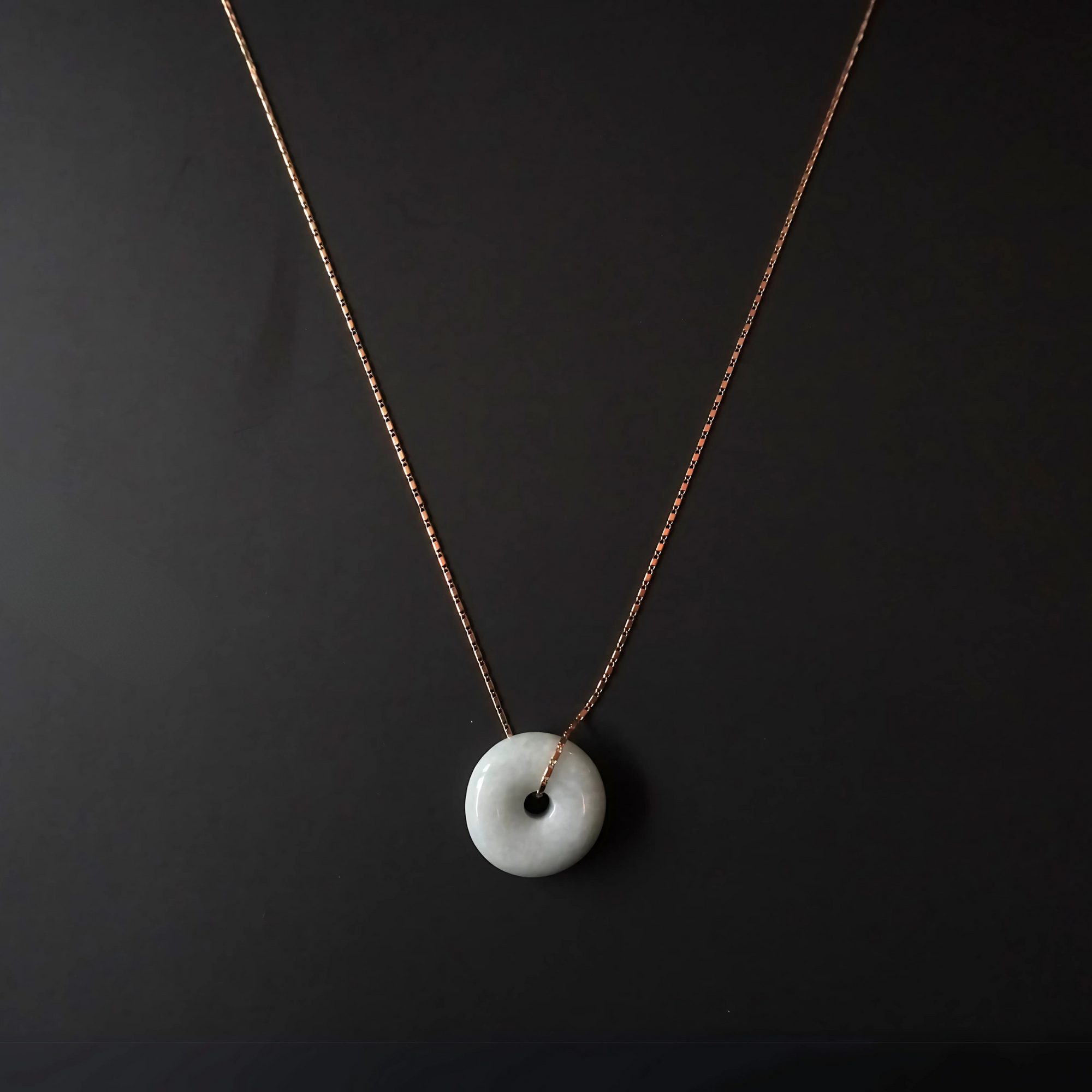 Flat lay of Yuán Jade Necklace with solid jade pendant and delicate gold chain.