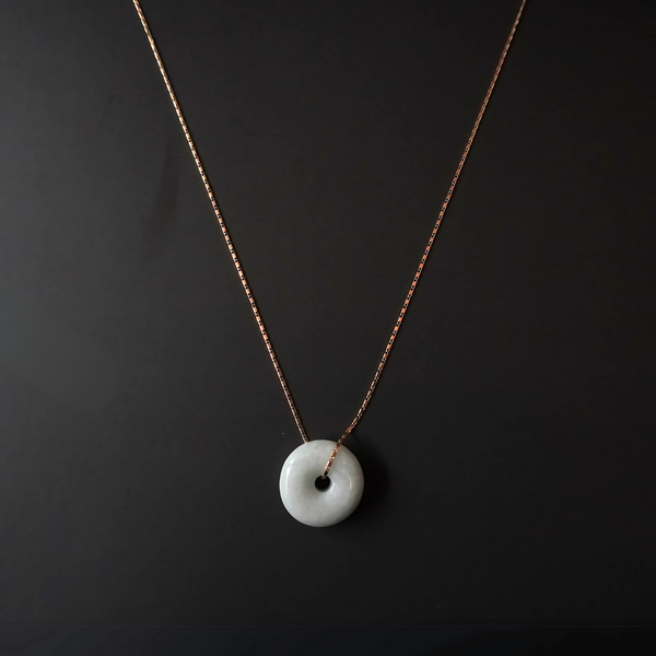 Flat lay of Yuán Jade Necklace with solid jade pendant and delicate gold chain.