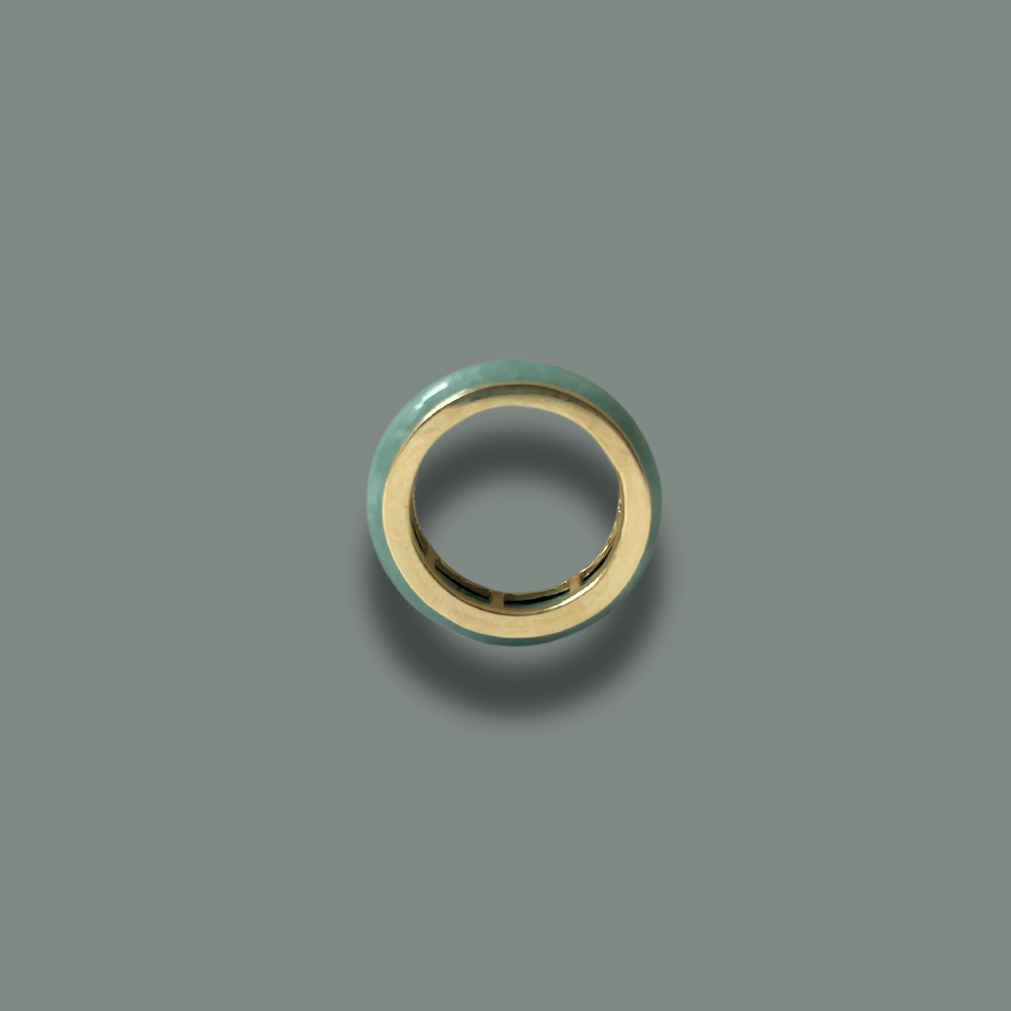 Jaura Ring crafted from solid gold and natural certified jadeite, displayed on a dark green background.
